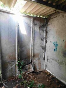 Inside concrete battery garage showing broken panels